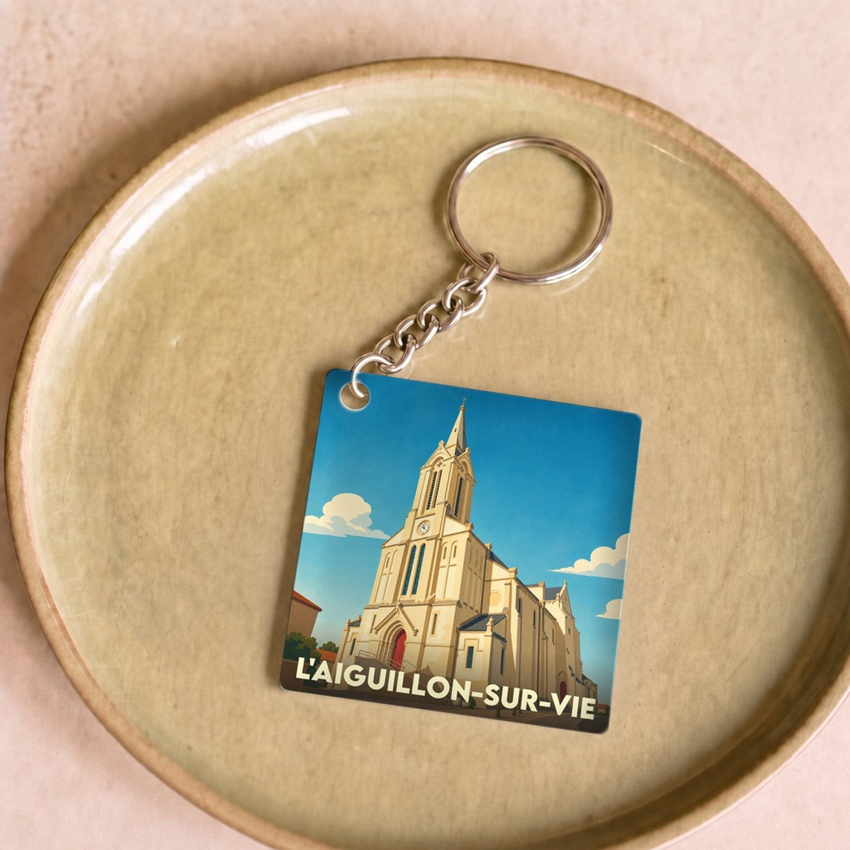 Porte-clés souvenir de la ville de L'Aiguillon-sur-Vie avec une illustration stylisée de son église.