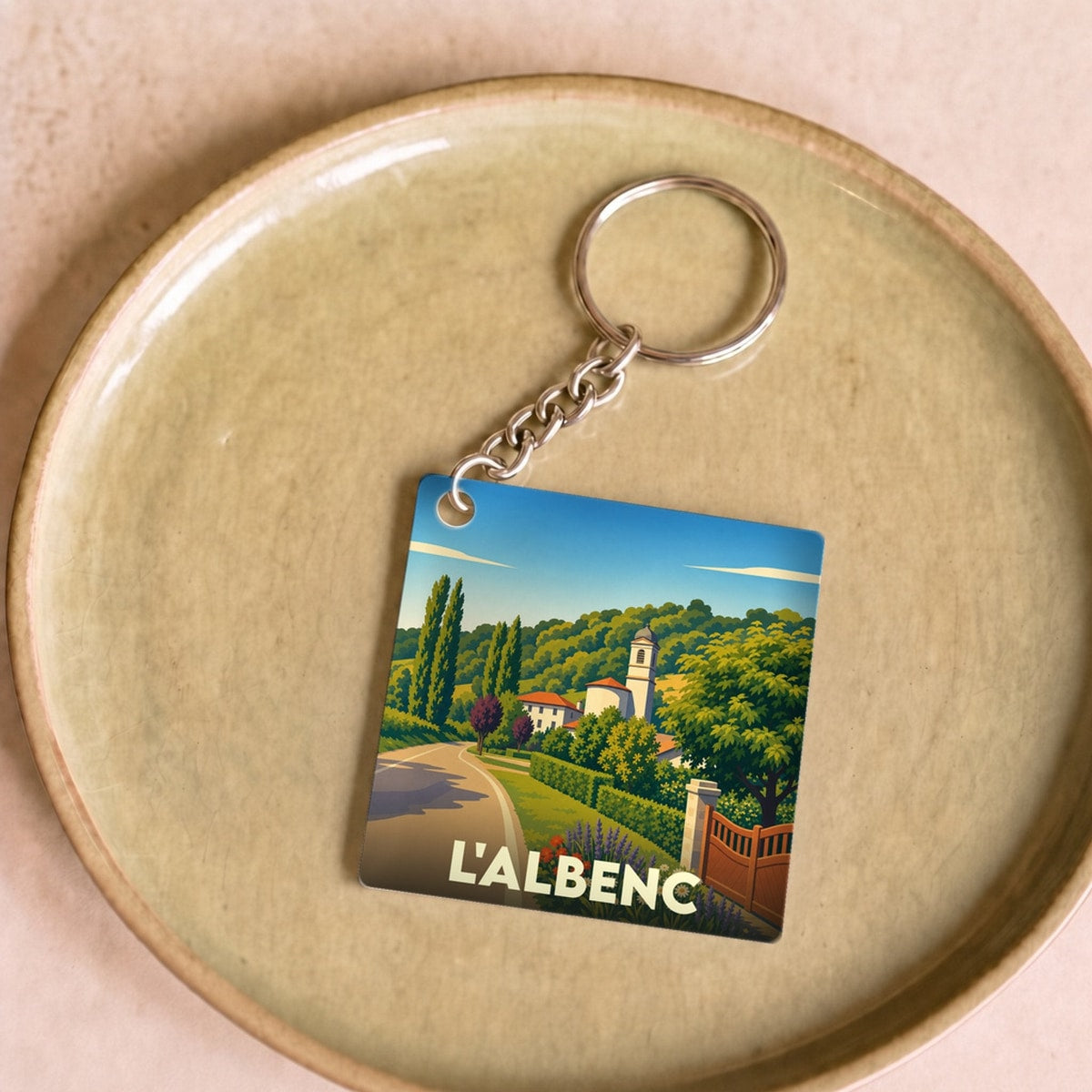Porte-clés souvenir de la ville de L'Albenc avec une illustration stylisée d'un paysage provençal.