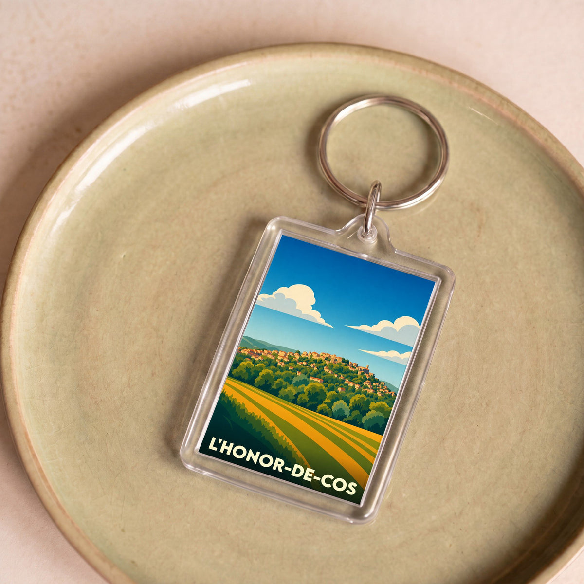 Porte-clés souvenir de la ville de L'Honor-de-Cos avec une illustration stylisée.