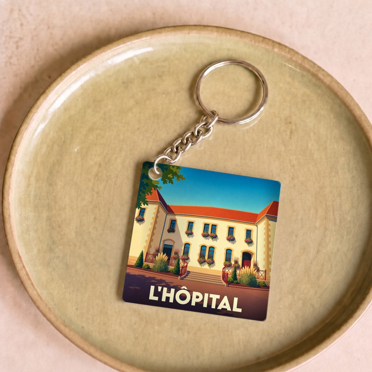 Porte-clés souvenir de la ville de L'Hôpital avec une illustration stylisée.