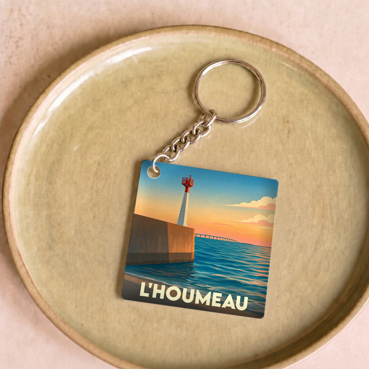 Porte-clés souvenir de la ville de L'Houmeau avec une illustration stylisée de son littoral au coucher du soleil.