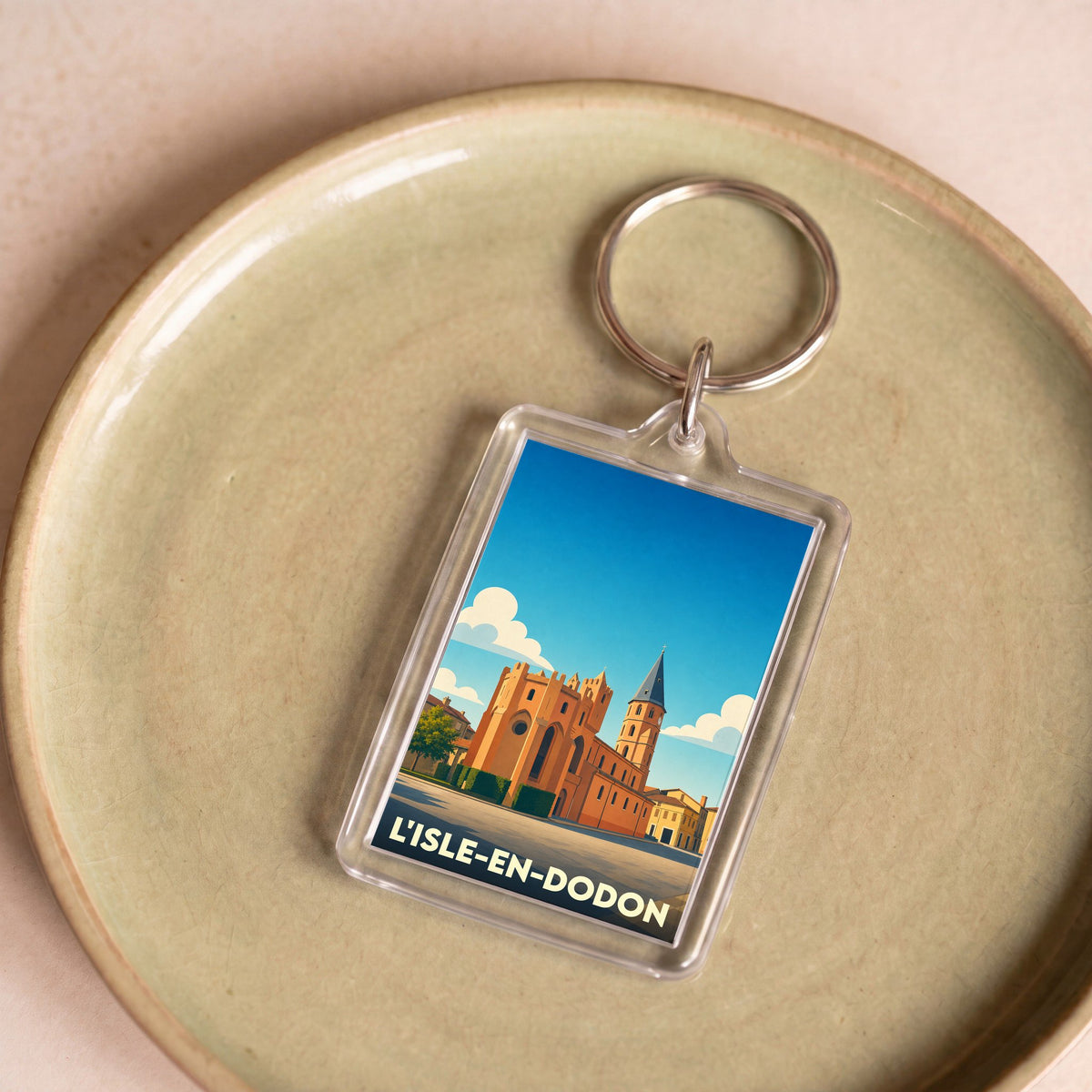 Porte-clés souvenir de la ville de L'Isle-en-Dodon avec une illustration stylisée de son église fortifiée.