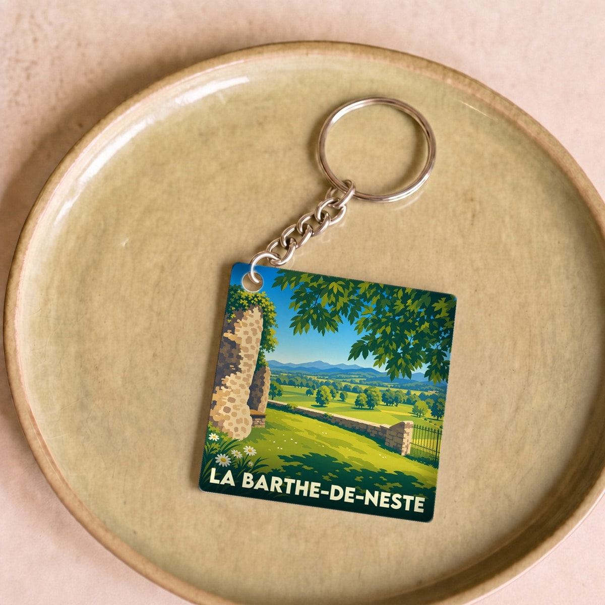 Porte-clés souvenir de La Barthe-de-Neste avec une illustration stylisée d'un paysage de campagne.