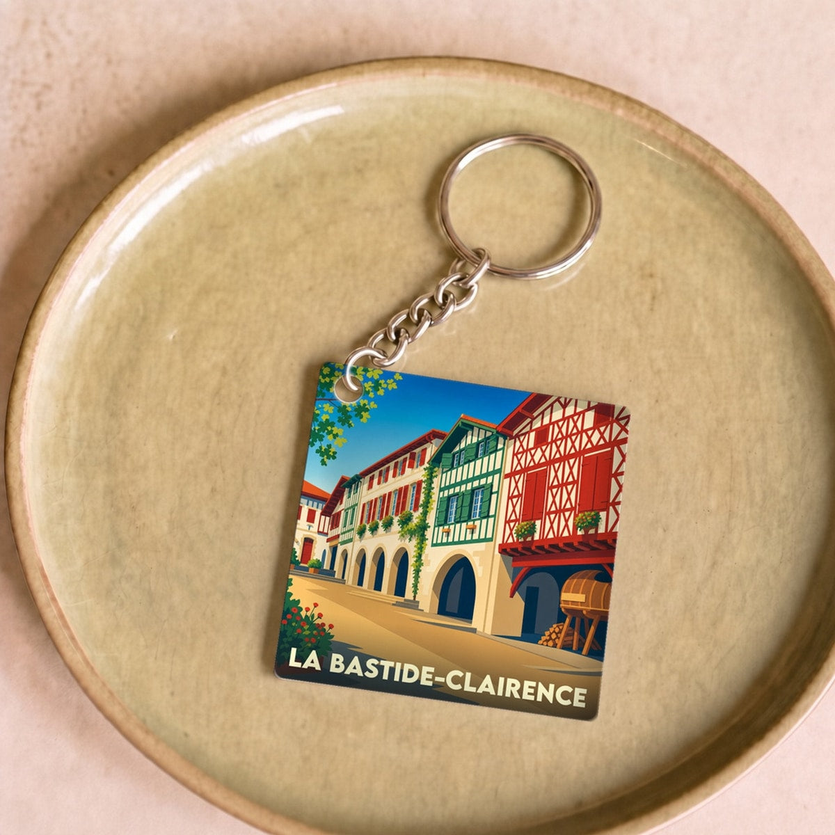 Porte-clés souvenir de la ville de La Bastide-Clairence avec une illustration stylisée de ses maisons à colombages.
