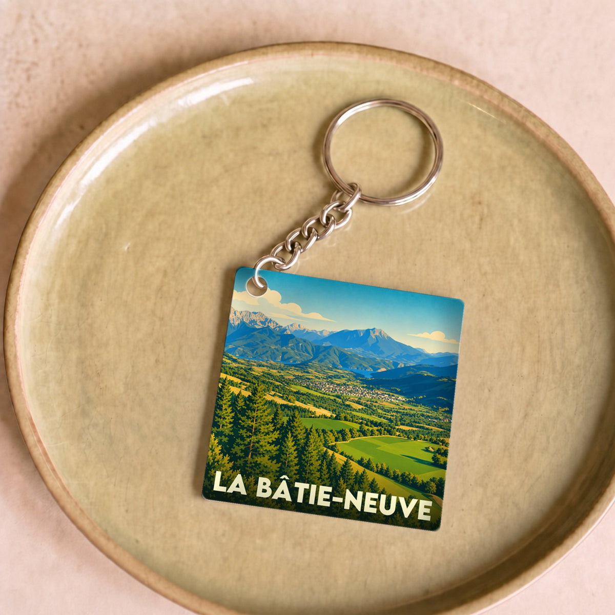 Porte-clés souvenir de la ville de La Bâtie-Neuve avec une illustration paysagère stylisée.
