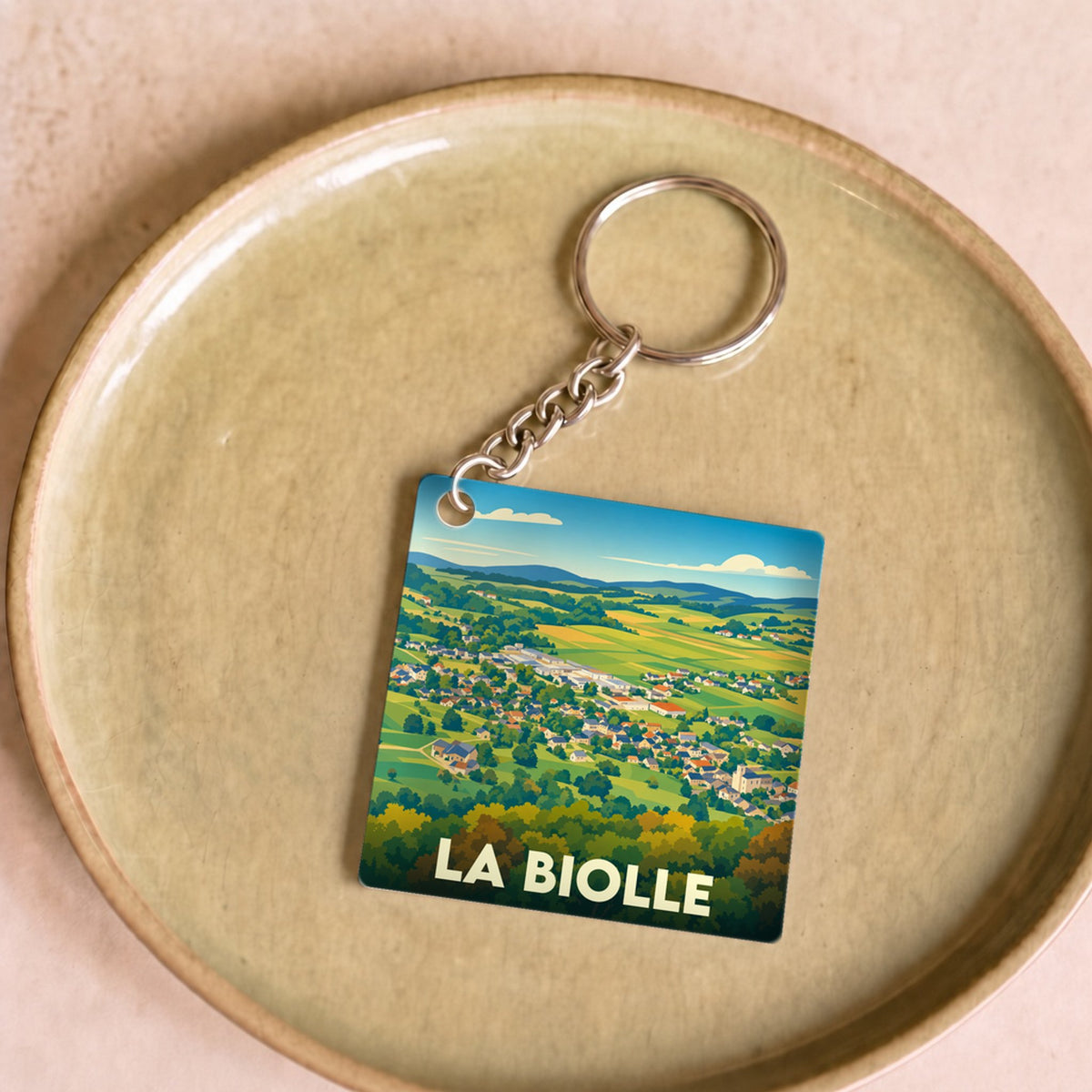 Porte-clés souvenir de la ville de La Biolle avec une illustration stylisée de son paysage.