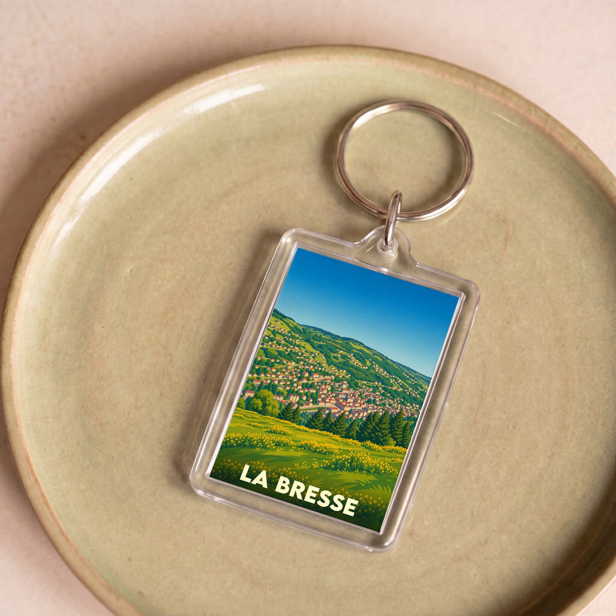 Porte-clés souvenir de la ville de La Bresse avec une illustration stylisée d'un paysage de montagne.