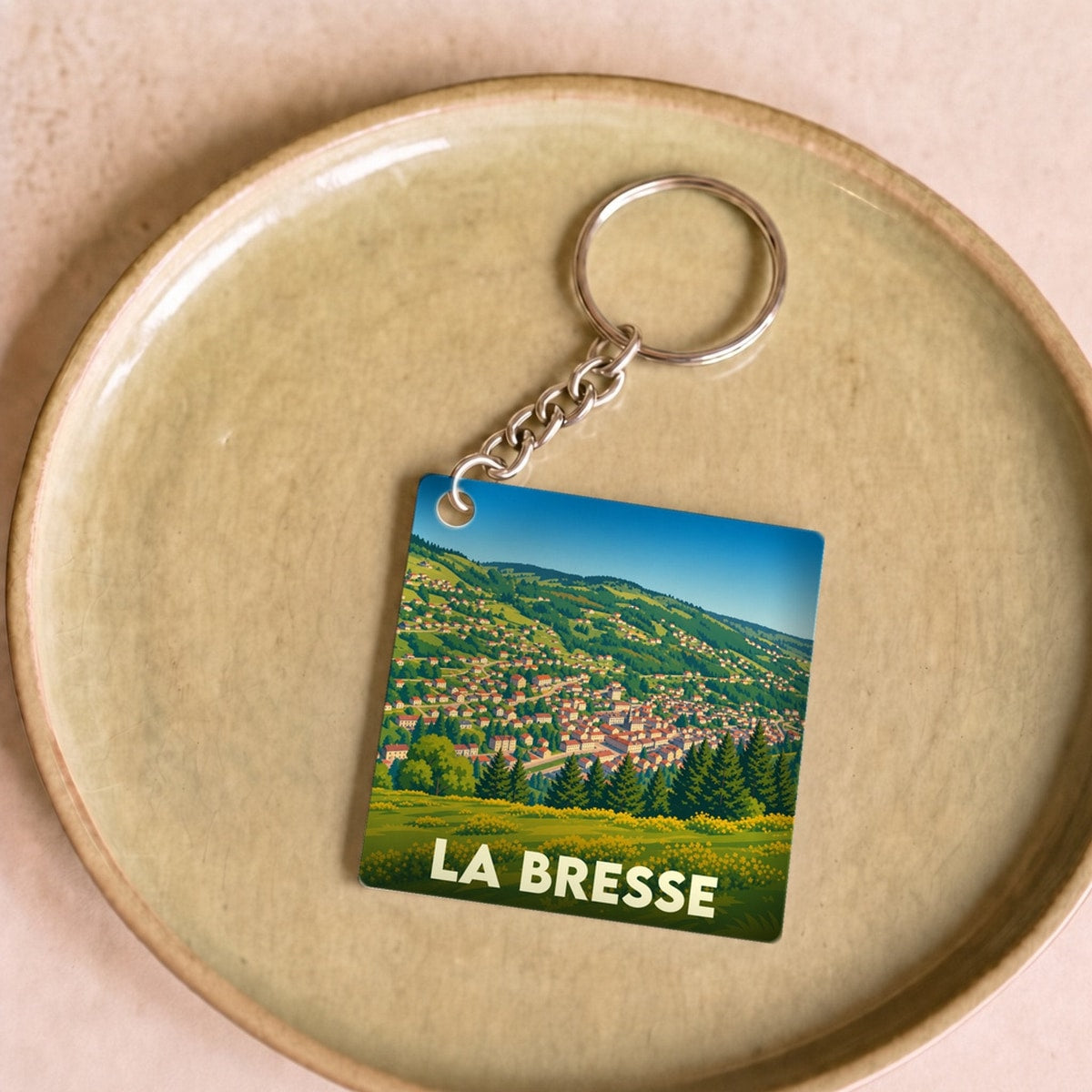 Porte-clés souvenir de la ville de La Bresse avec une illustration stylisée d'un paysage montagneux.