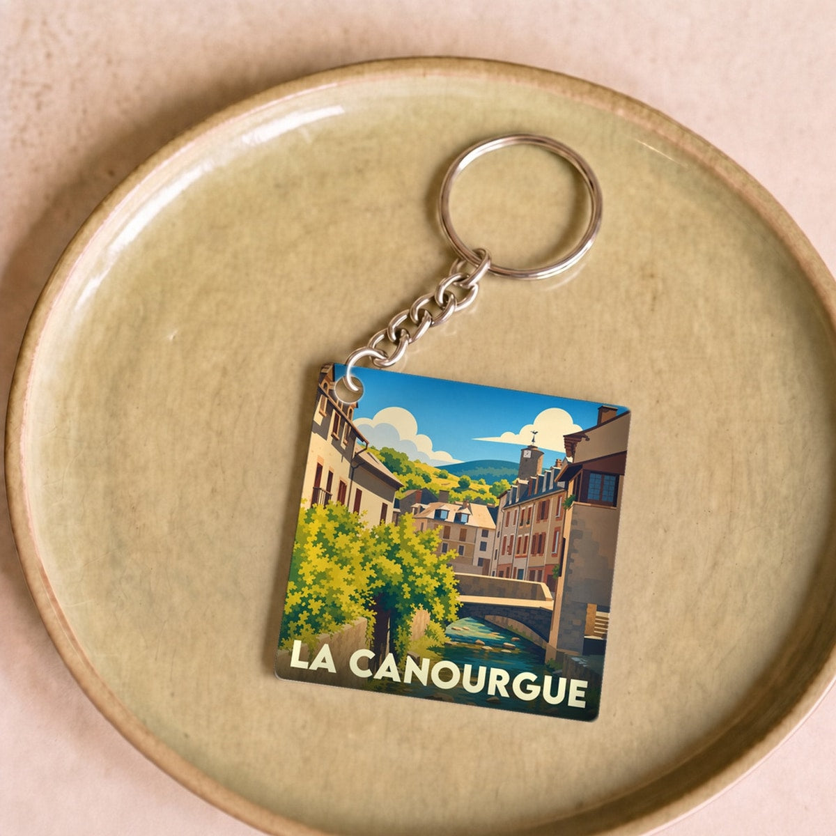 Porte-clés souvenir de la ville de La Canourgue avec une illustration stylisée.