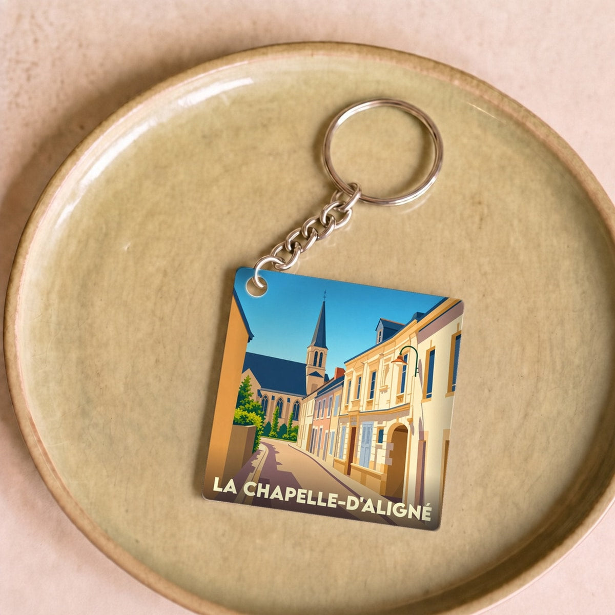 Porte-clés souvenir de la ville de La Chapelle-d'Aligné avec une illustration stylisée.