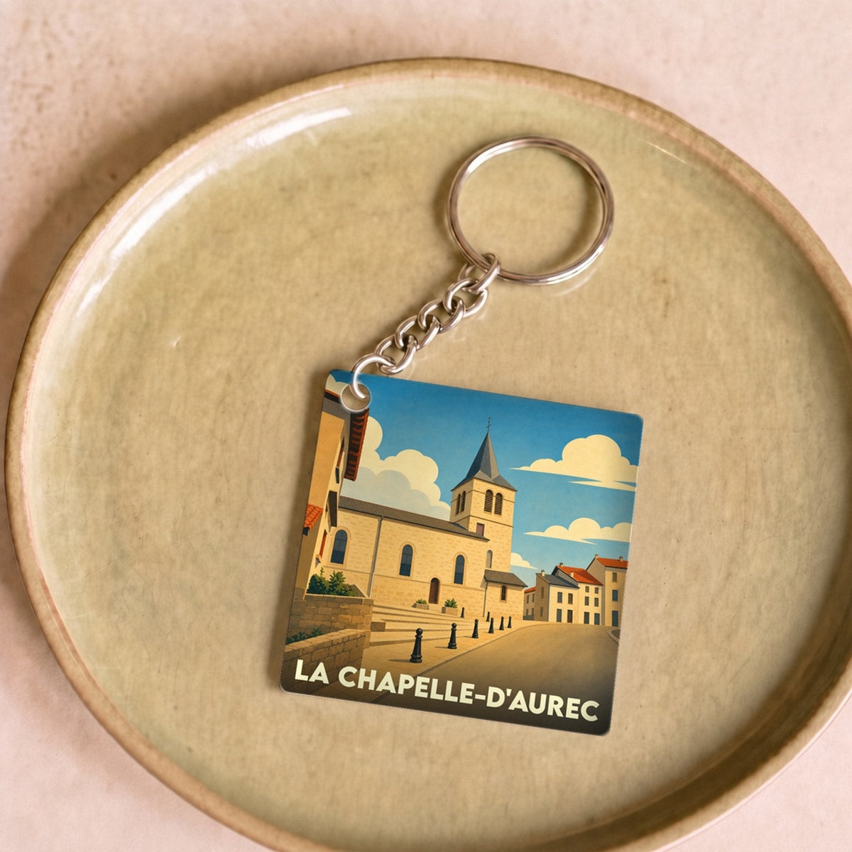 Porte-clés souvenir de la ville de La Chapelle-d'Aurec avec une illustration stylisée d'une église sous un ciel bleu.