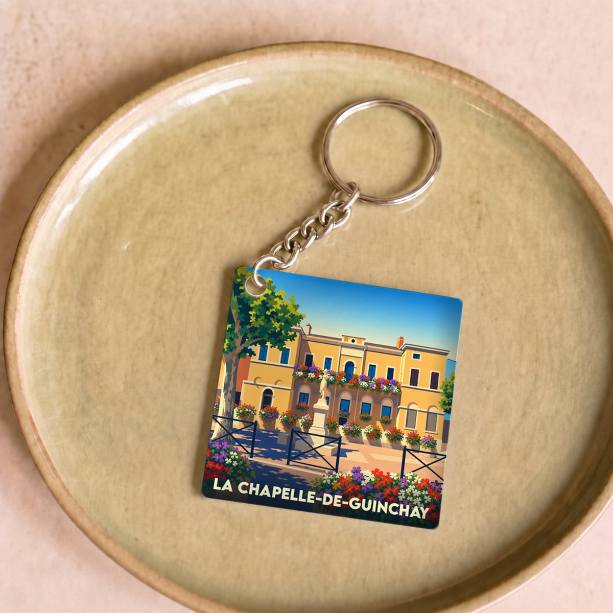 Porte-clés souvenir de la ville de La Chapelle-de-Guinchay avec une illustration colorée et stylisée.
