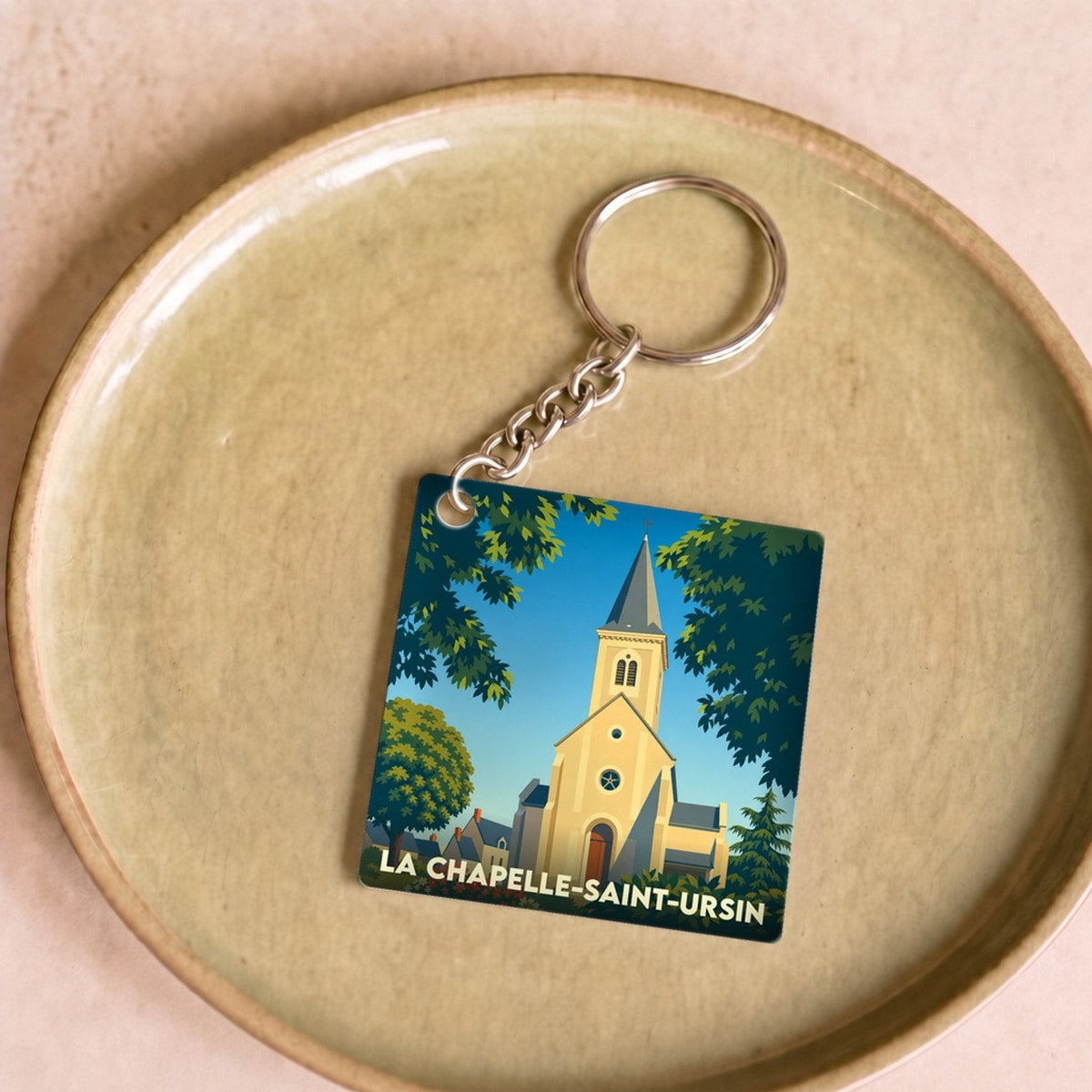 Porte-clés souvenir de la ville de La Chapelle-Saint-Ursin avec une illustration stylisée de son église.