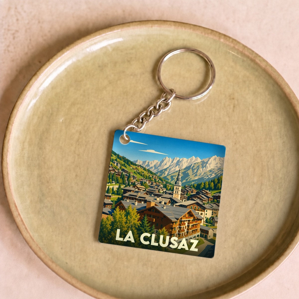 Porte-clés souvenir de la ville de La Clusaz avec une illustration stylisée de montagne.