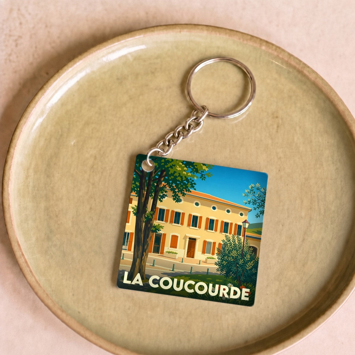 Porte-clés souvenir de la ville de La Coucourde avec une illustration colorée et stylisée.