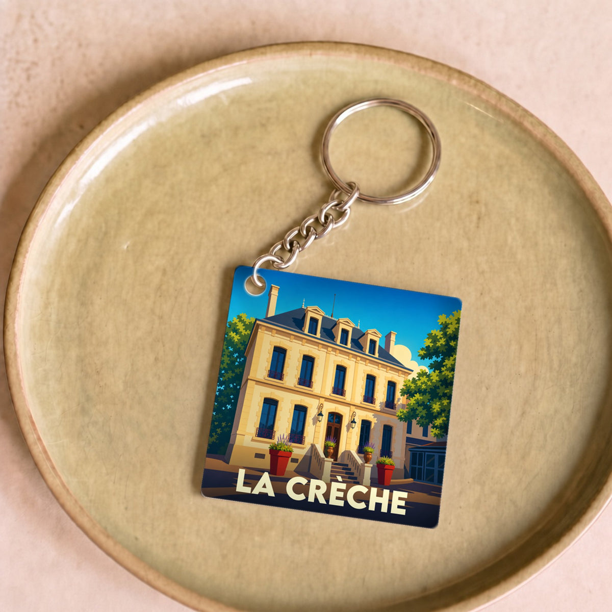 Porte-clés souvenir de la ville de La Crèche avec une illustration stylisée d'un bâtiment historique.