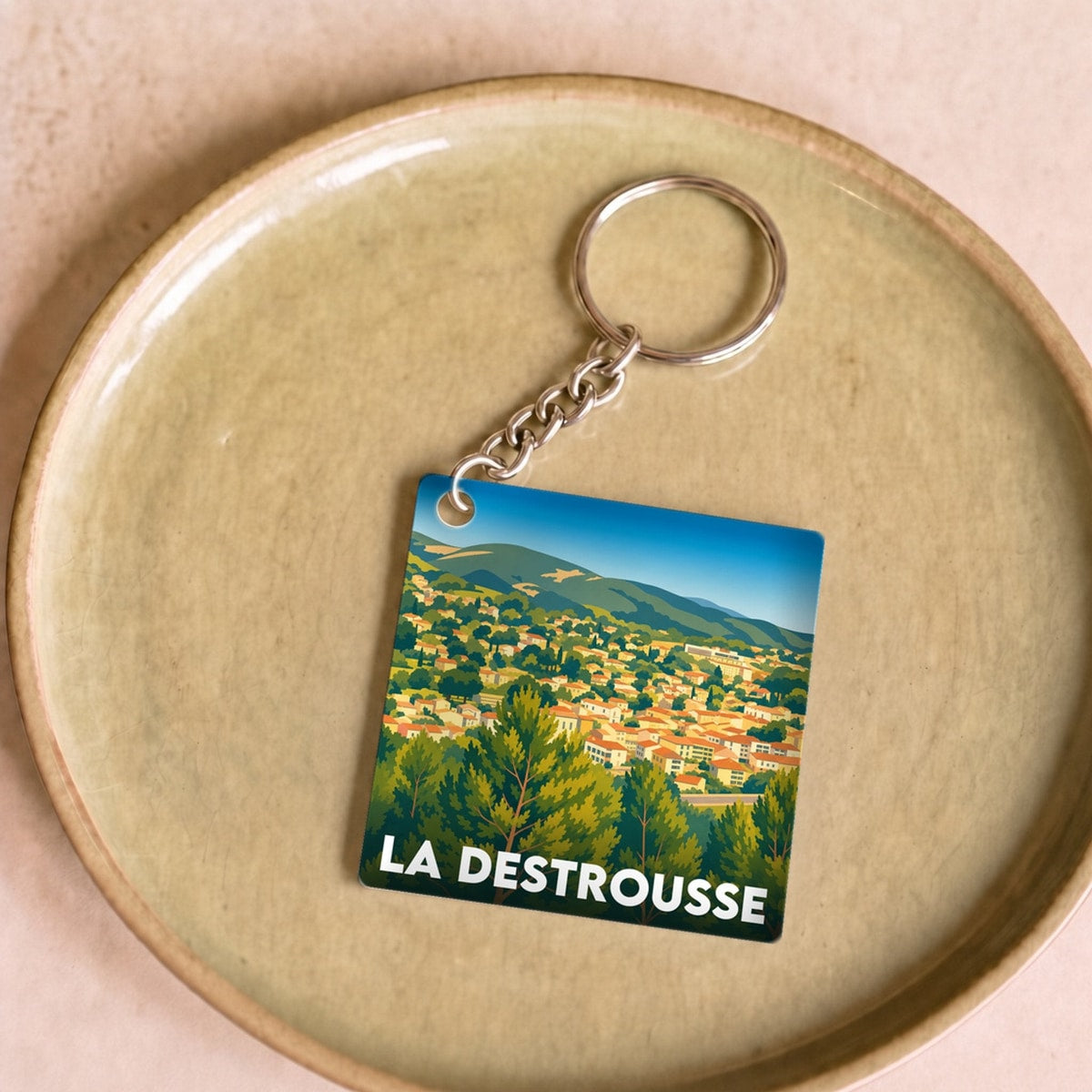 Porte-clés souvenir de la ville de La Destrousse avec une illustration stylisée du paysage.