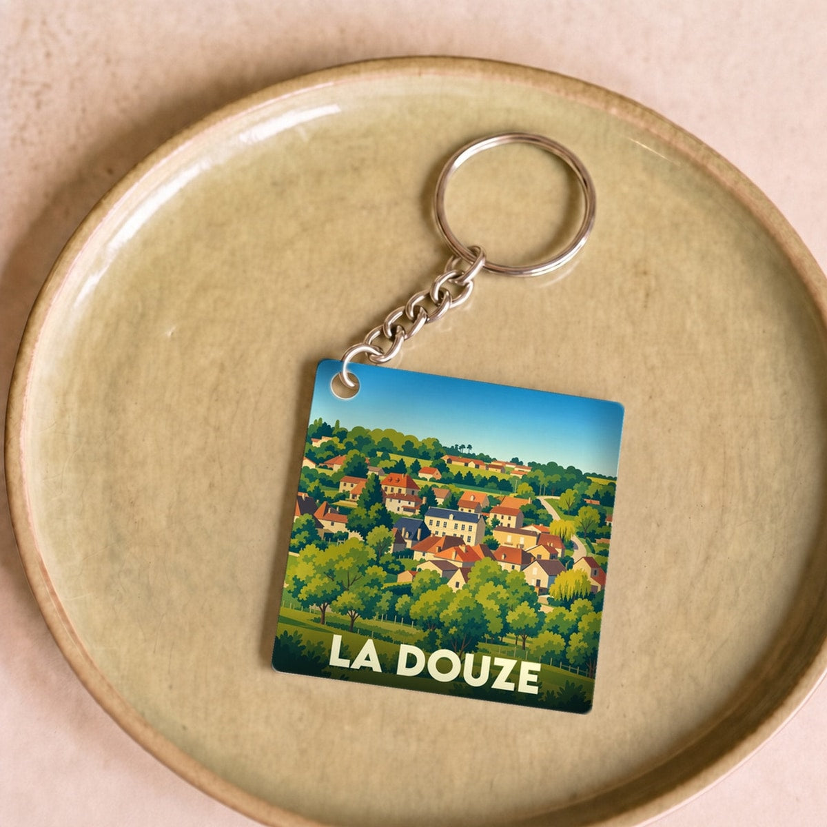 Porte-clés souvenir de la ville de La Douze avec une illustration stylisée d'un village vallonné.