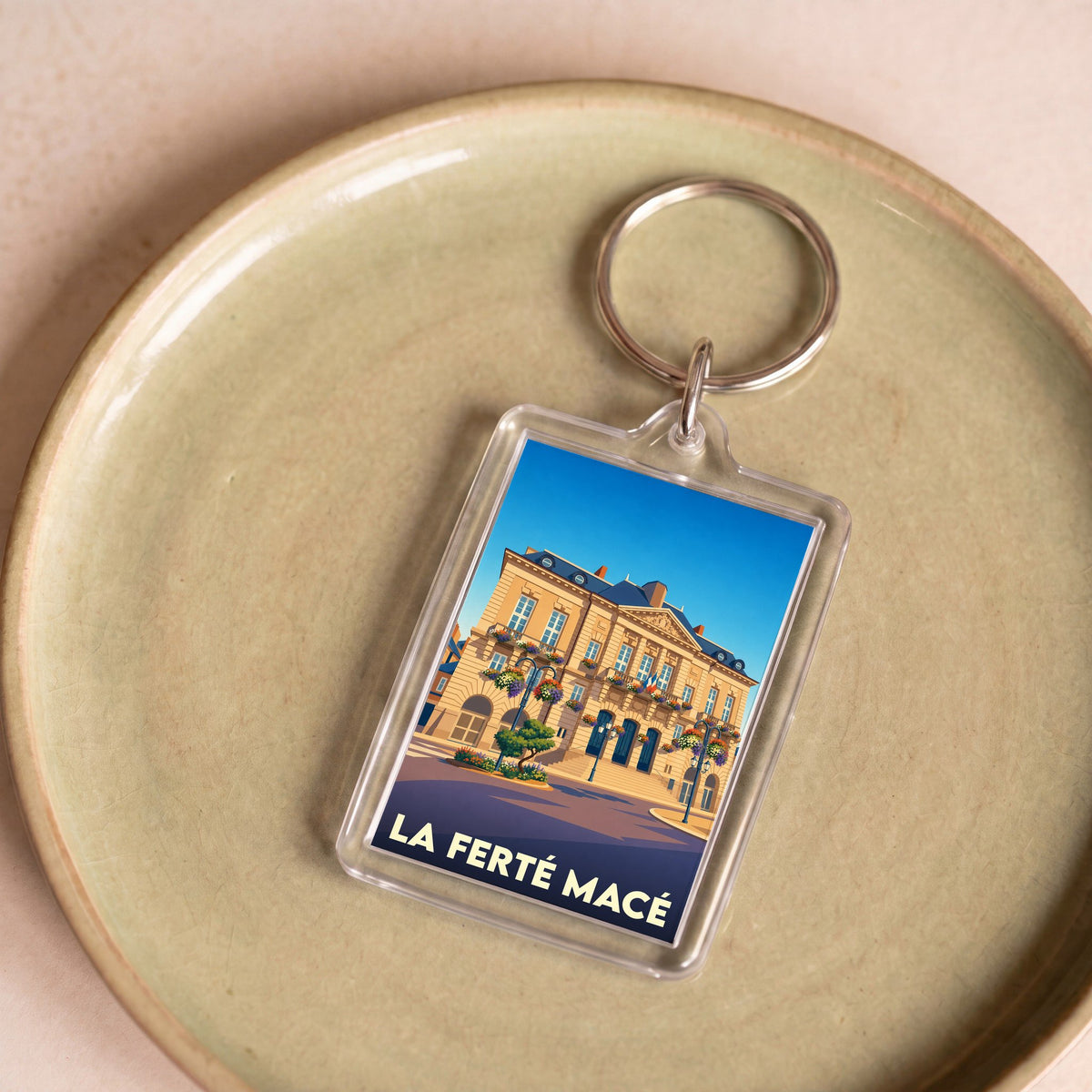 Porte-clés souvenir de la ville de La Ferté-Macé avec une illustration stylisée de l'hôtel de ville.
