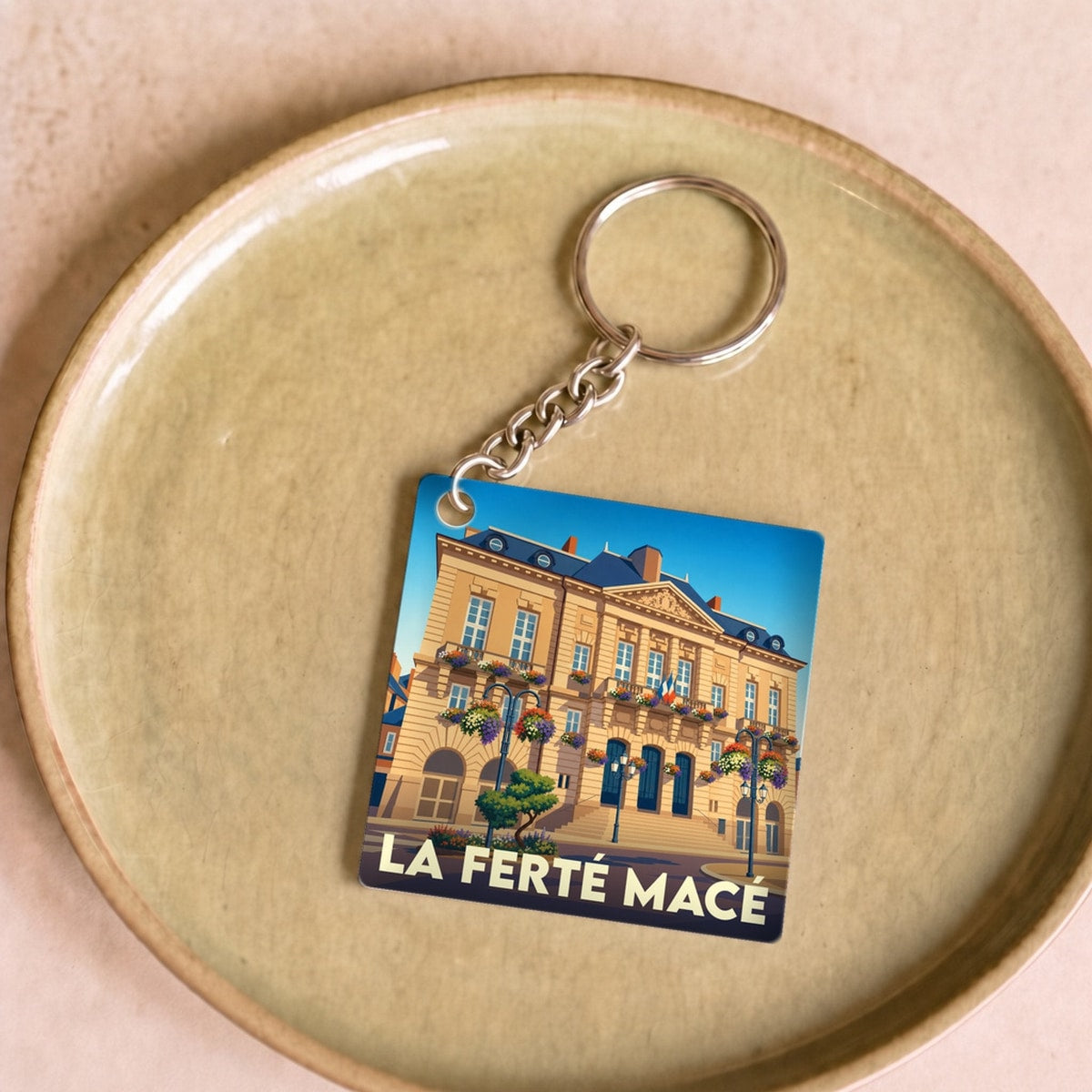 Porte-clés souvenir de la ville de La Ferté Macé avec une illustration stylisée de son hôtel de ville.