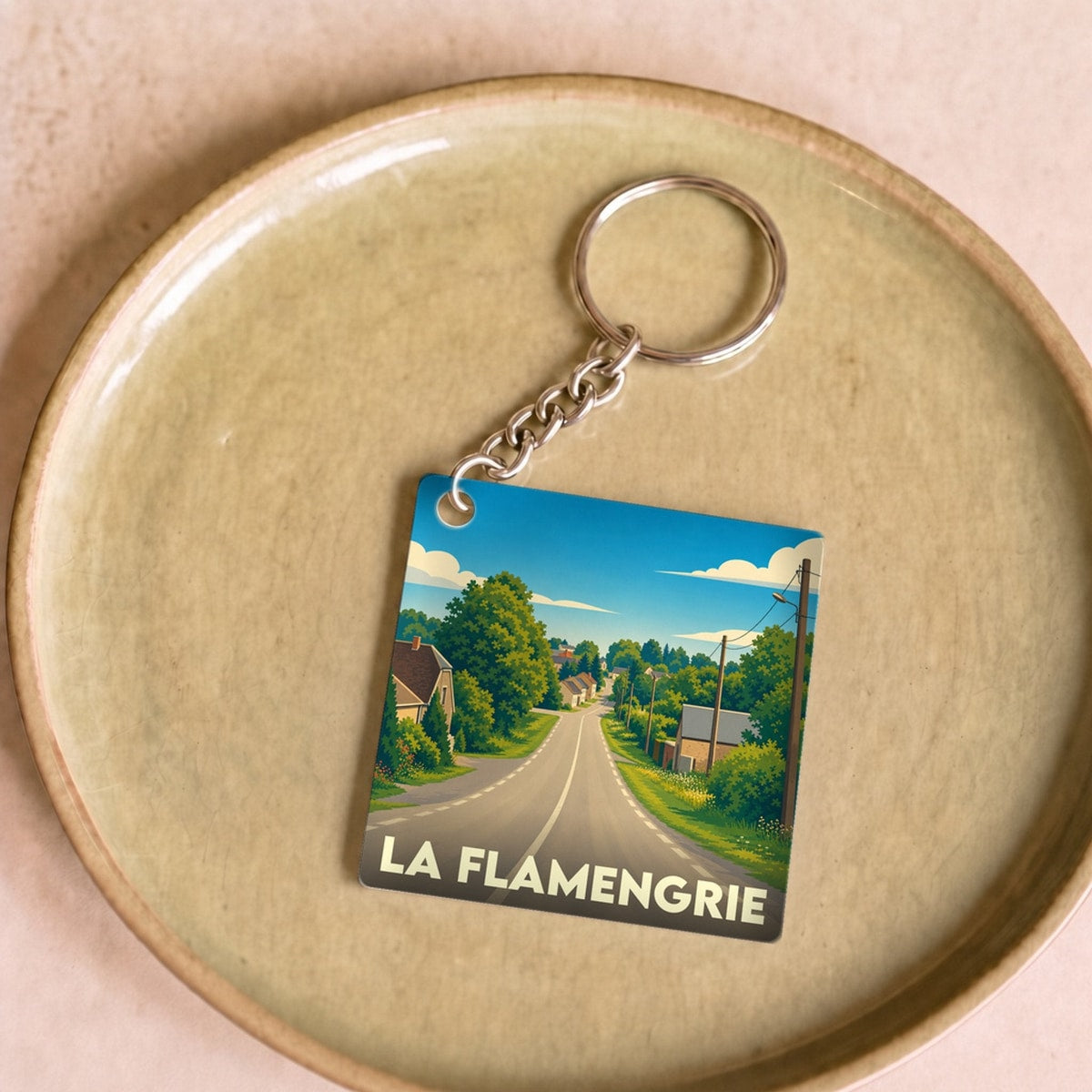 Porte-clés souvenir de la ville de La Flamengrie avec une illustration stylisée.