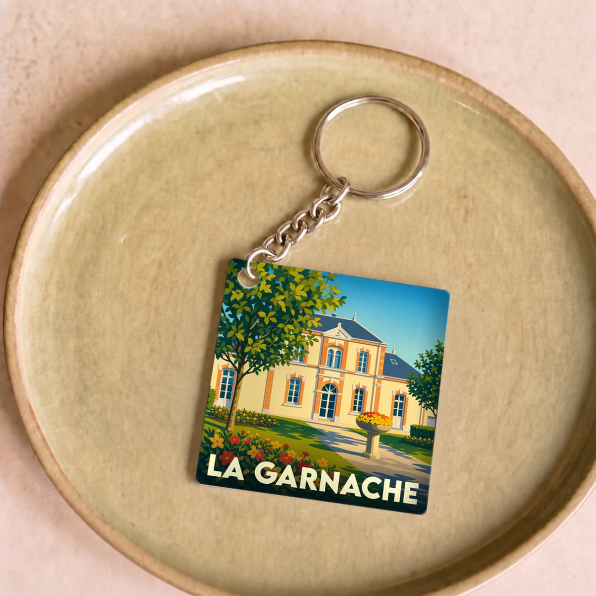 Porte-clés souvenir de la ville de La Garnache avec une illustration stylisée d'un château fleuri.