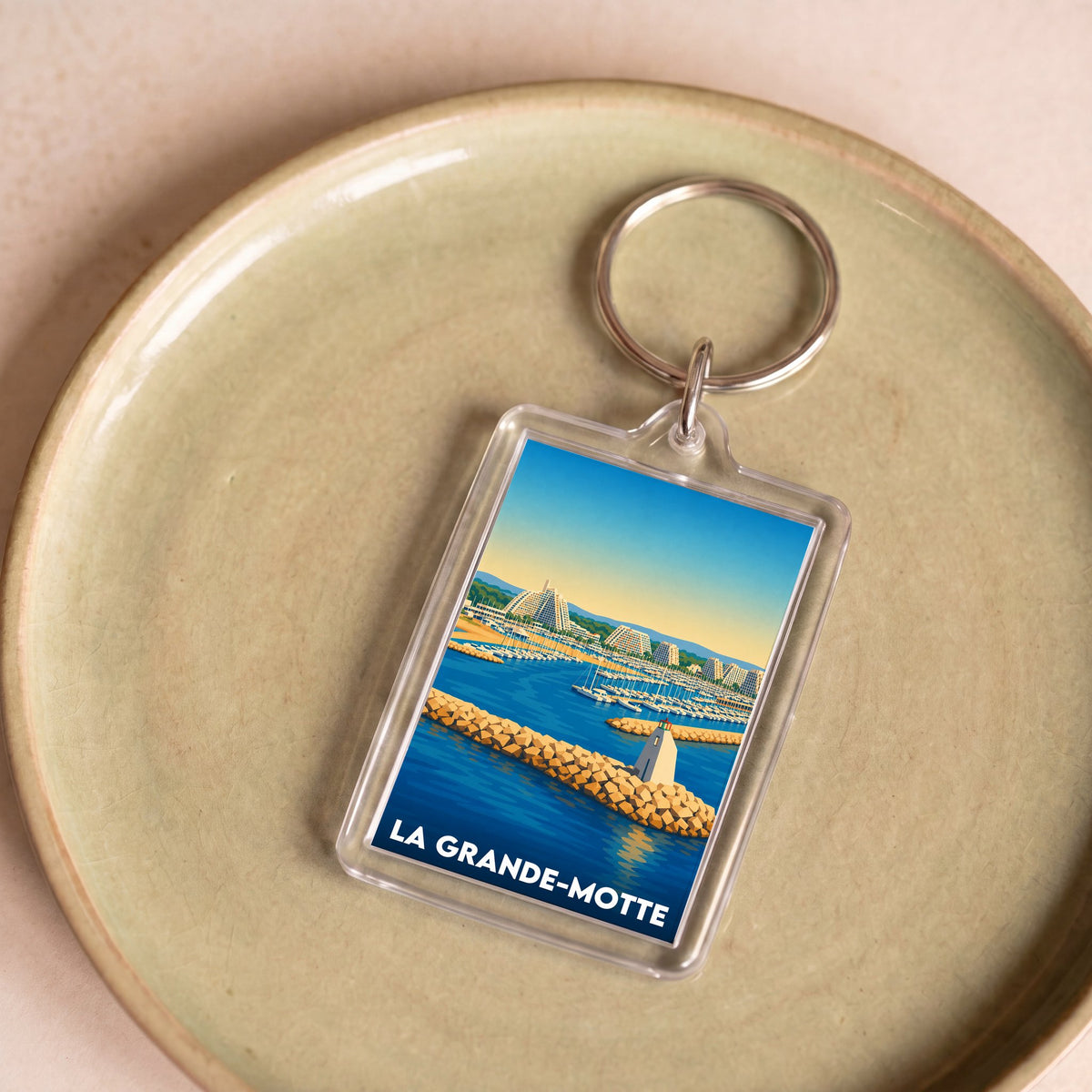 Porte-clés souvenir de la ville de La Grande-Motte avec une illustration stylisée.