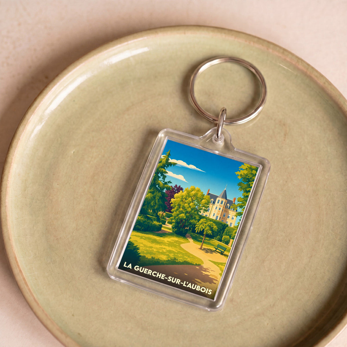 Porte-clés souvenir de la ville de La Guerche-sur-l'Aubois avec une illustration stylisée d'un parc et d'un château.