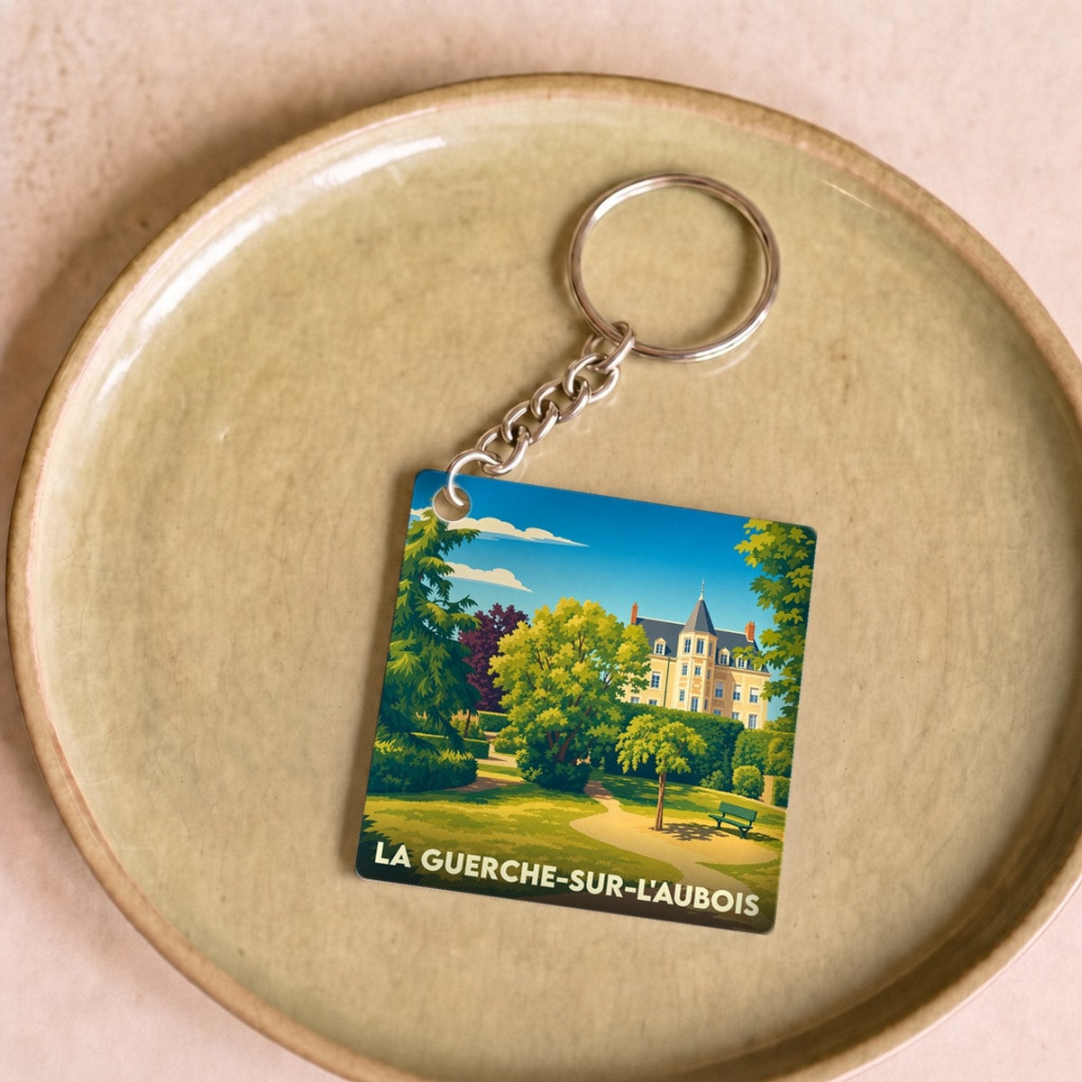 Porte-clés souvenir de la ville de La Guerche-sur-l'Aubois avec une illustration stylisée d'un parc et d'un château.