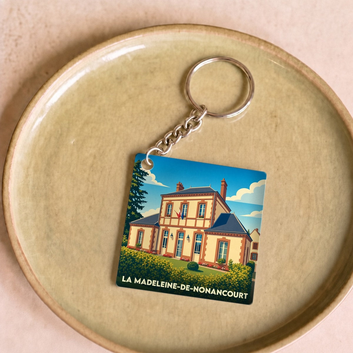 Porte-clés souvenir de la ville de La Madeleine-de-Nonancourt avec une illustration stylisée de sa mairie.