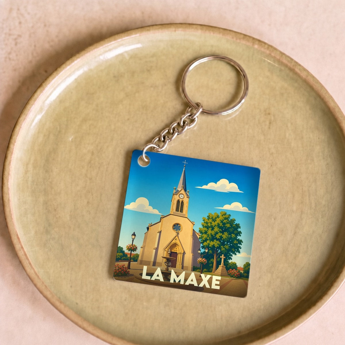 Porte-clés souvenir de la ville de La Maxe avec une illustration stylisée de son église.