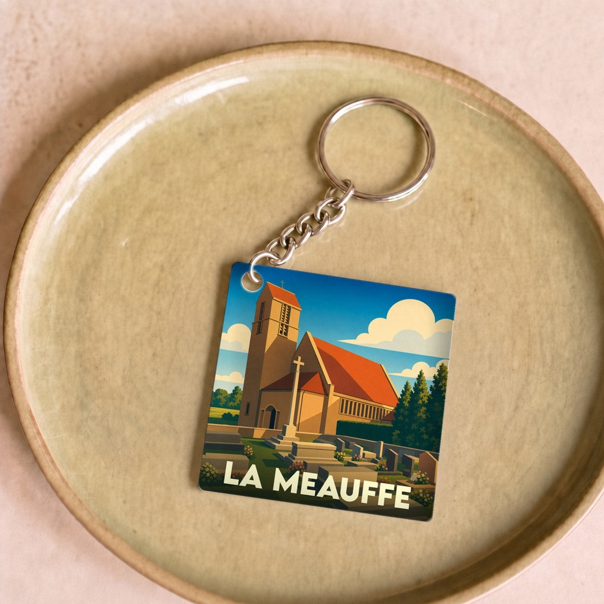 Porte-clés souvenir de la ville de La Meauffe avec une illustration stylisée de son église.