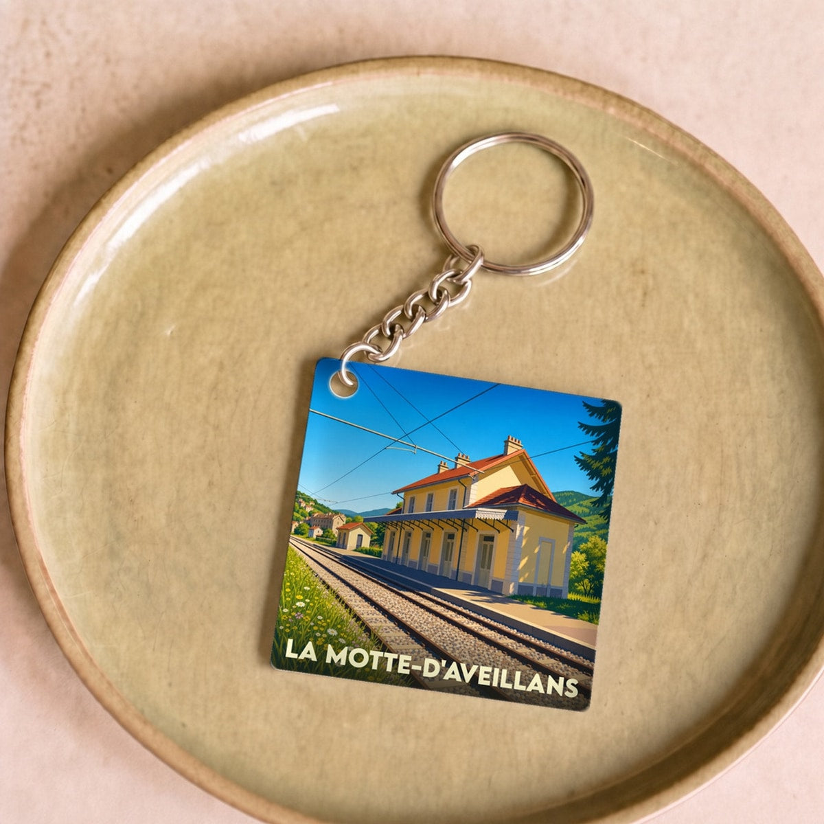 Porte-clés souvenir de la ville de La Motte-d'Aveillans avec une illustration stylisée de sa gare ferroviaire.