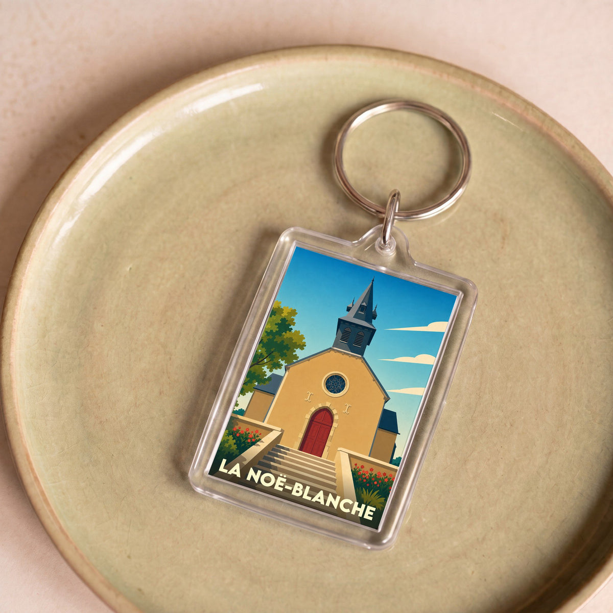 Porte-clés souvenir de la ville de La Noë-Blanche avec une illustration stylisée de son église.