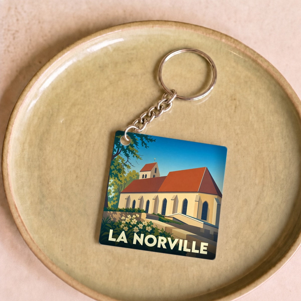Porte-clés souvenir de la ville de La Norville avec une illustration stylisée de son église.