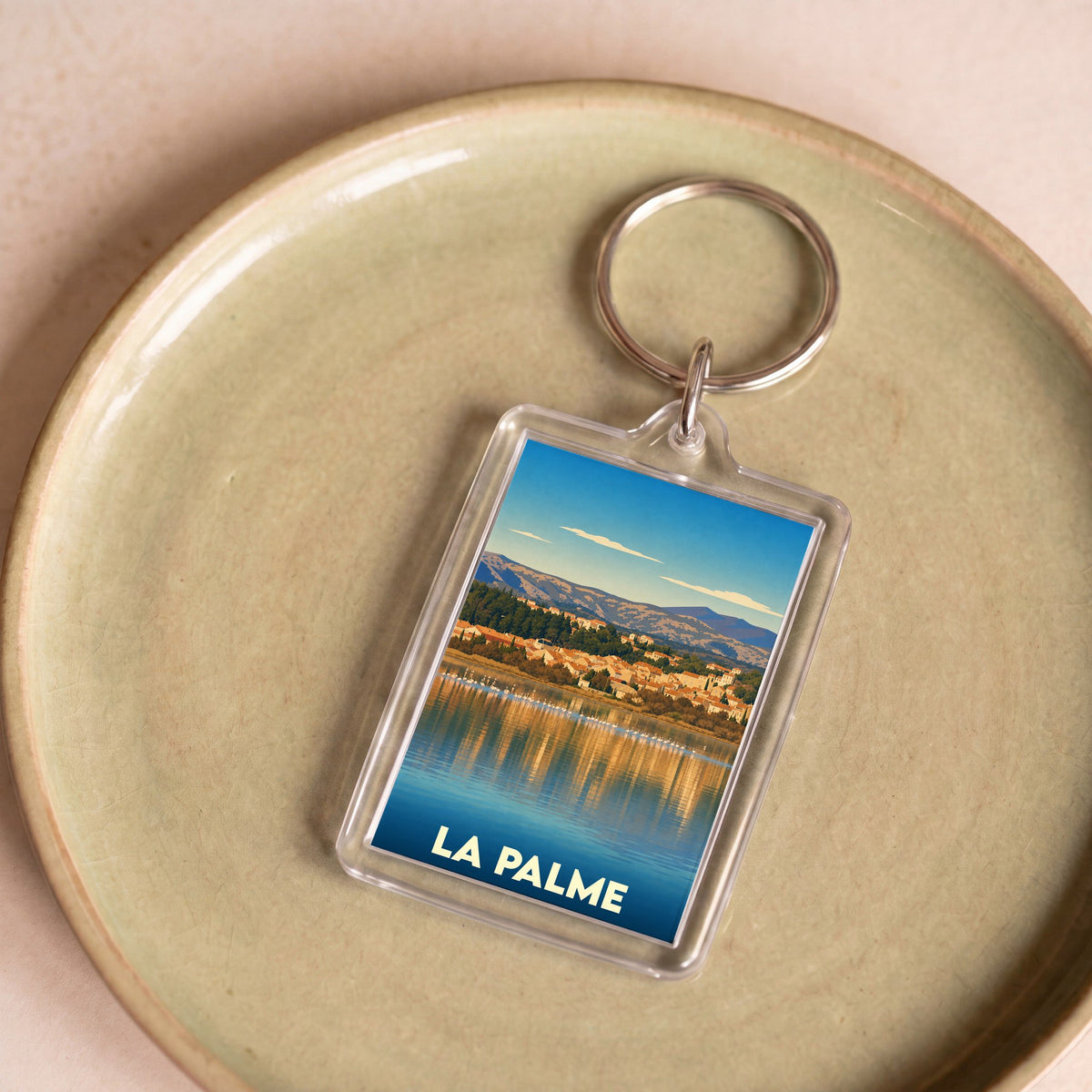 Porte-clés souvenir de la ville de La Palme avec une illustration stylisée d'un paysage lacustre.
