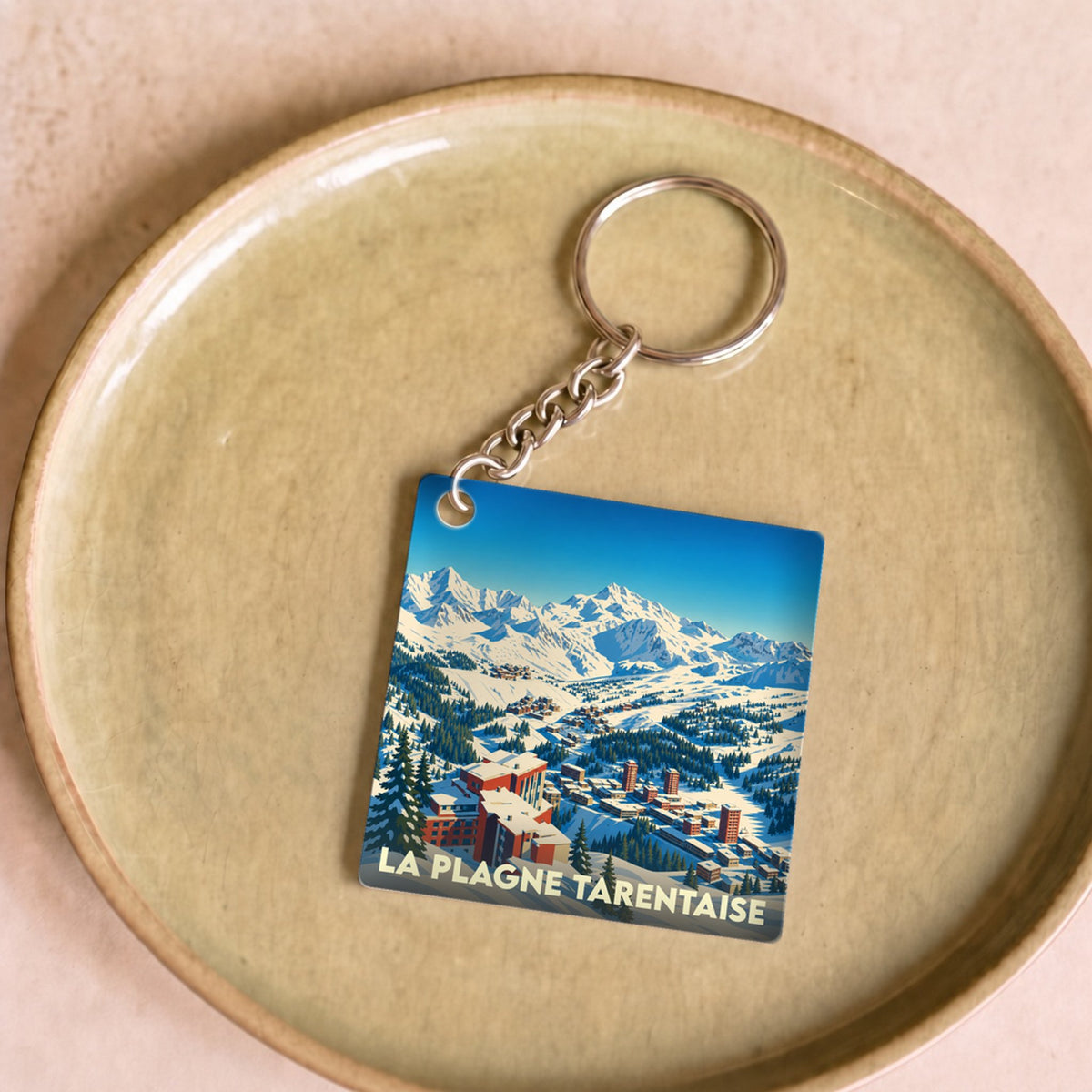 Porte-clés souvenir de La Plagne Tarentaise avec une illustration stylisée d'une station de ski enneigée.