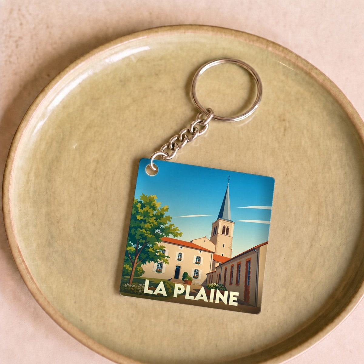 Porte-clés souvenir de la ville de La Plaine avec une illustration stylisée.