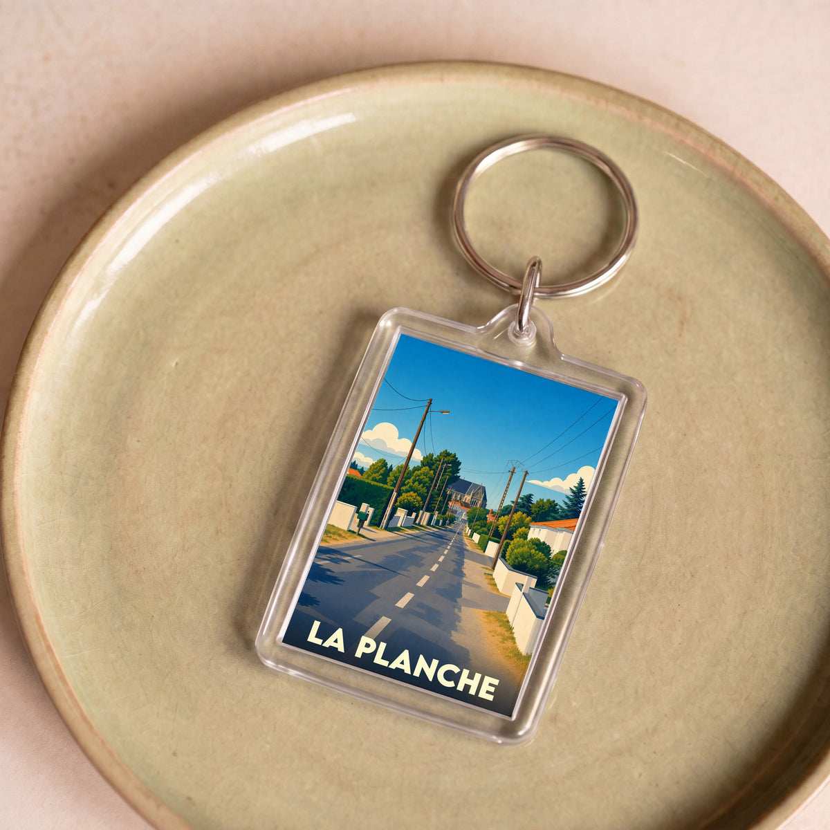 Porte-clés souvenir de la ville de La Planche avec une illustration stylisée d'une rue ensoleillée.
