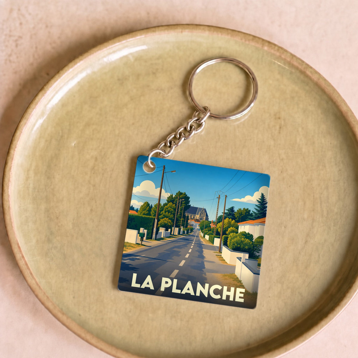 Porte-clés souvenir de la ville de La Planche avec une illustration stylisée d'une rue ensoleillée.