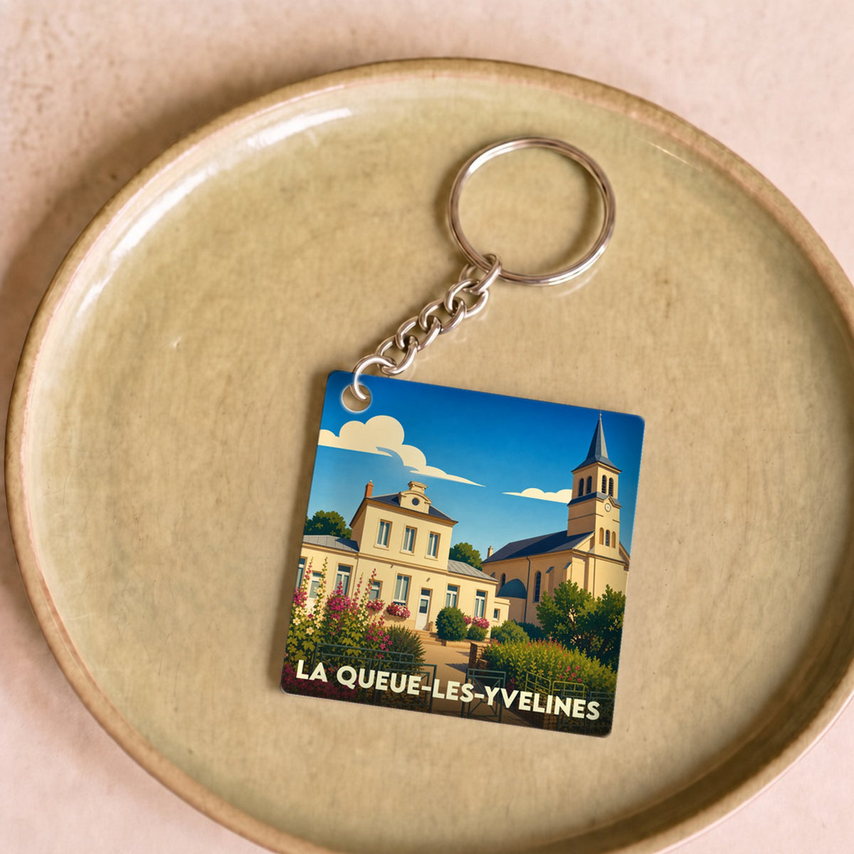 Porte-clés souvenir de la ville de La Queue-les-Yvelines avec une illustration stylisée.