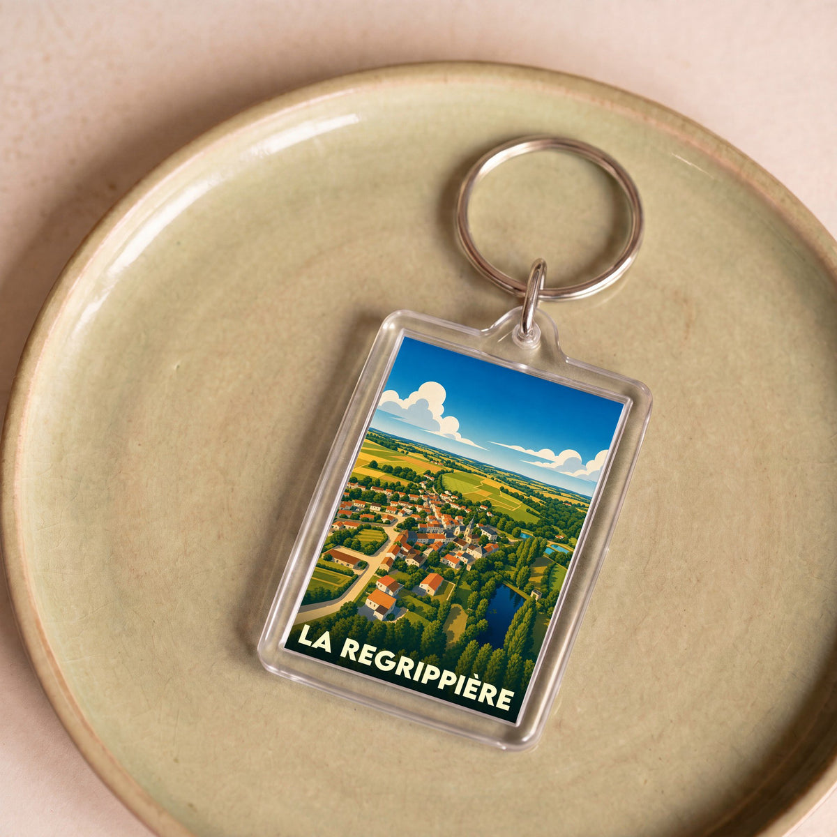 Porte-clés souvenir de la ville de La Regrippière avec une illustration stylisée d'un paysage rural.