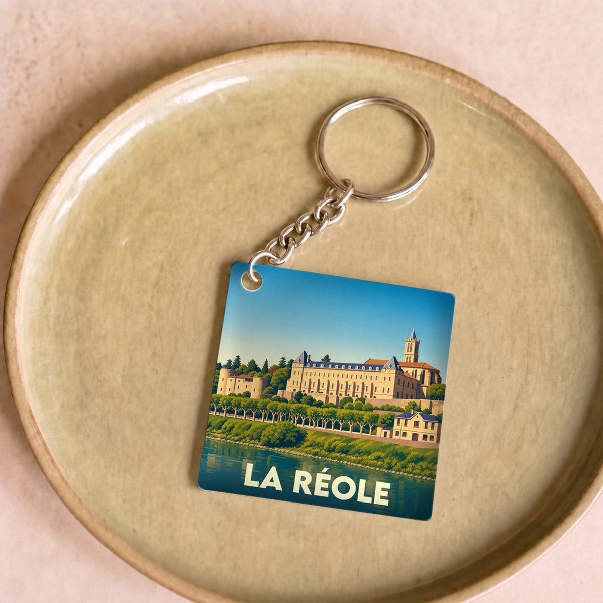 Porte-clés souvenir de la ville de La Réole avec une illustration stylisée du panorama sur la Garonne.