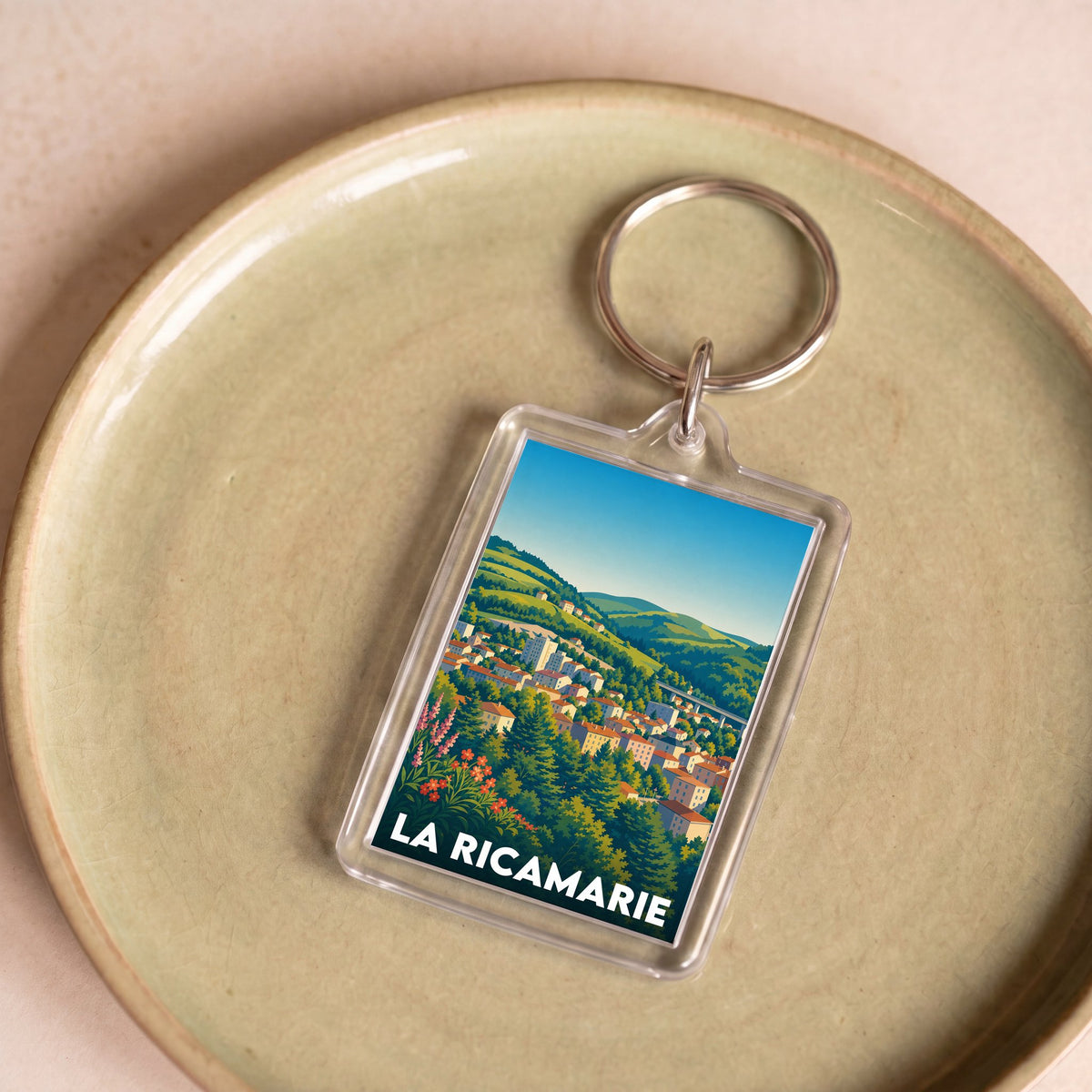 Porte-clés souvenir de la ville de La Ricamarie avec une illustration stylisée du paysage urbain.