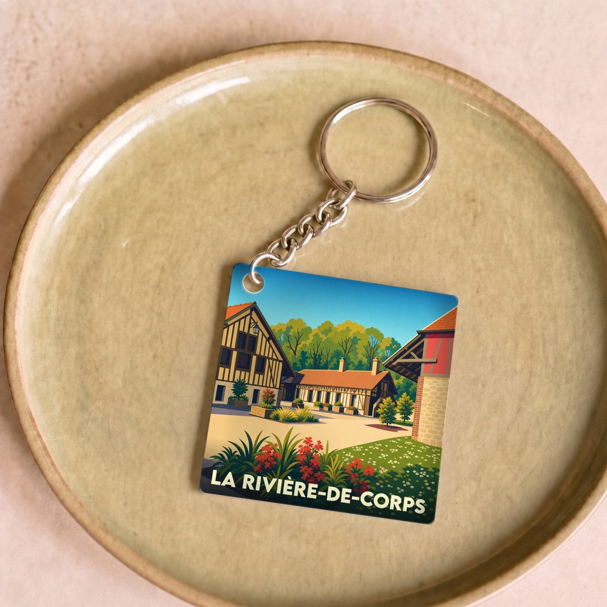 Porte-clés souvenir de la ville de La Rivière-de-Corps avec une illustration stylisée.