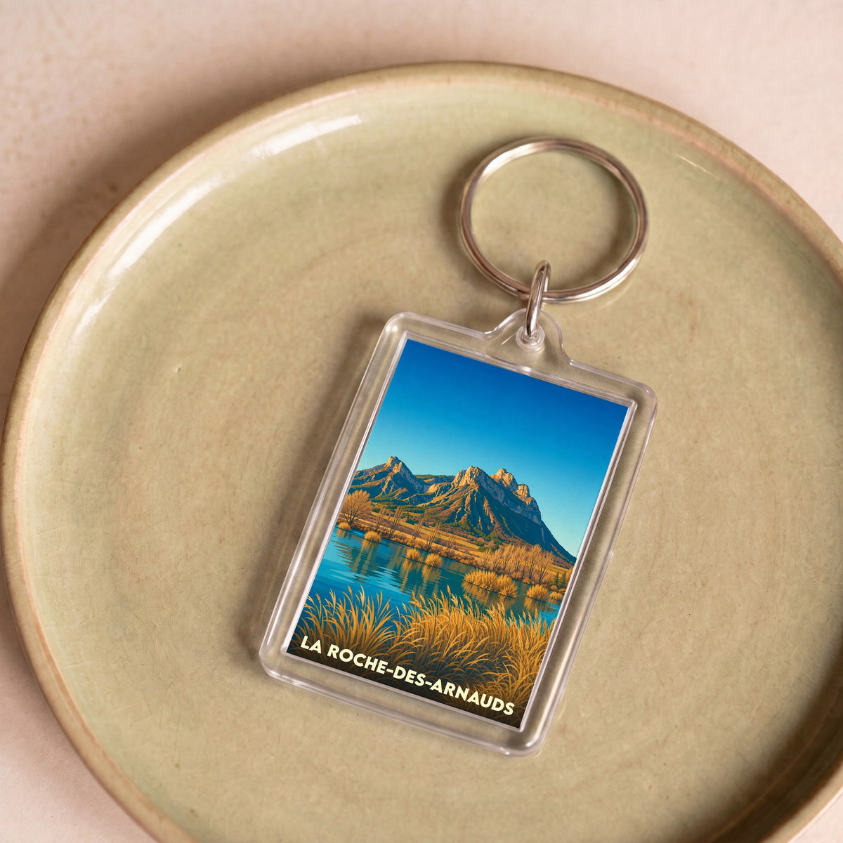 Porte-clés souvenir de la ville de La Roche-des-Arnauds avec une illustration de paysage montagneux.