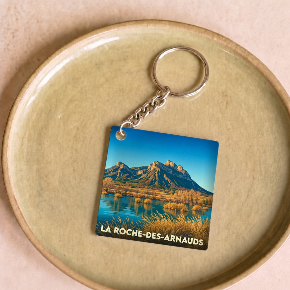Porte-clés souvenir de la ville de La Roche-des-Arnauds avec une illustration de paysage montagneux.