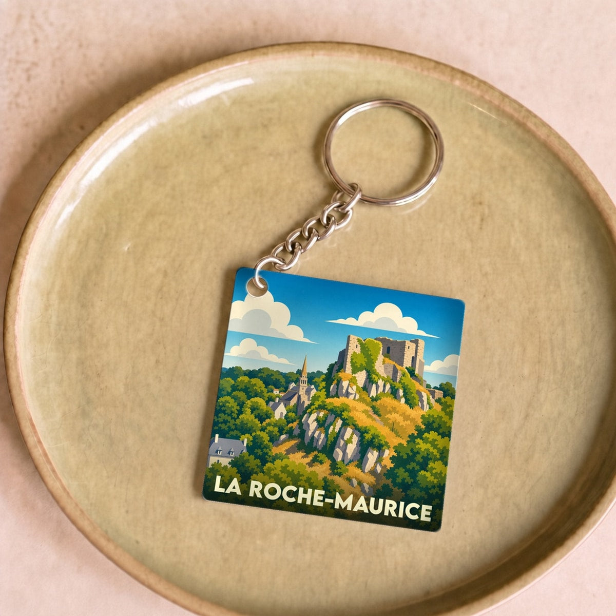Porte-clés souvenir de la ville de La Roche-Maurice avec une illustration stylisée de son château et de son paysage.