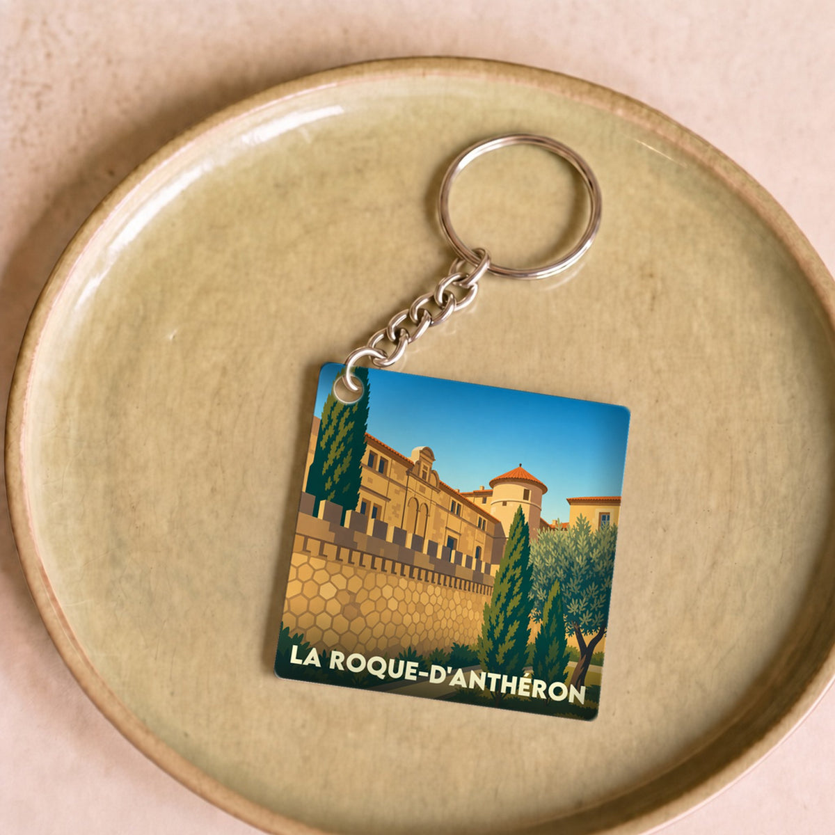 Porte-clés souvenir de la ville de La Roque-d'Anthéron avec une illustration stylisée.