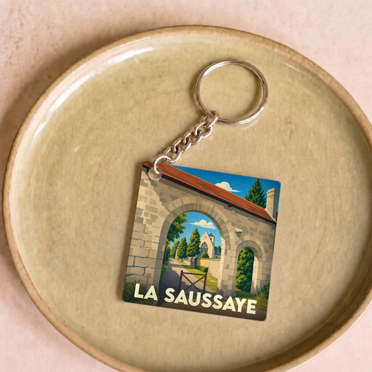 Porte-clés souvenir de la ville de La Saussaye avec une illustration stylisée d'un porche médiéval.